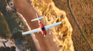 Cirrus SR series plane flying over the west coast during fall.