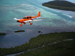 Cirrus SR Series G7 aircraft flying above shallow turquoise water and coastal islands